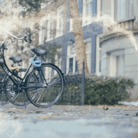 a bicycle is parked on a sidewalk in front of a building that says swagfiets on the bottom right