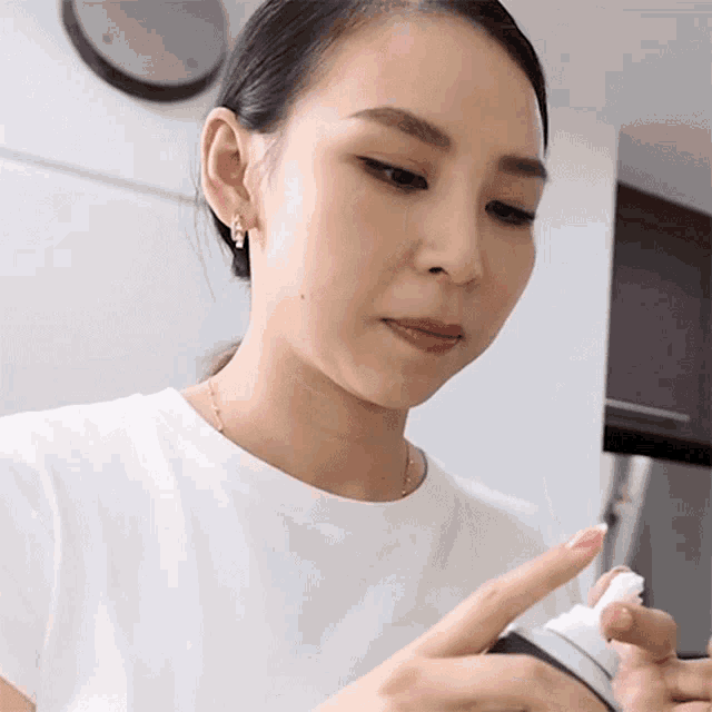a woman in a white shirt is holding a bottle of lotion