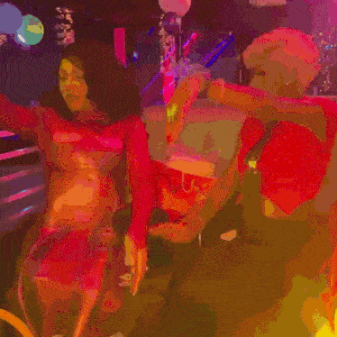 a group of people are dancing in a room with balloons in the shape of a heart