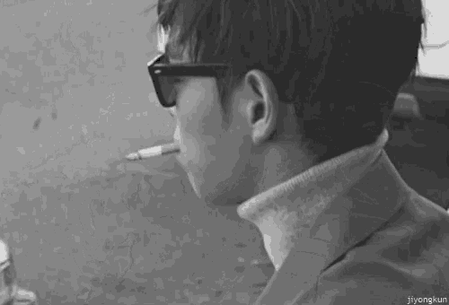 a man wearing sunglasses is smoking a cigarette .