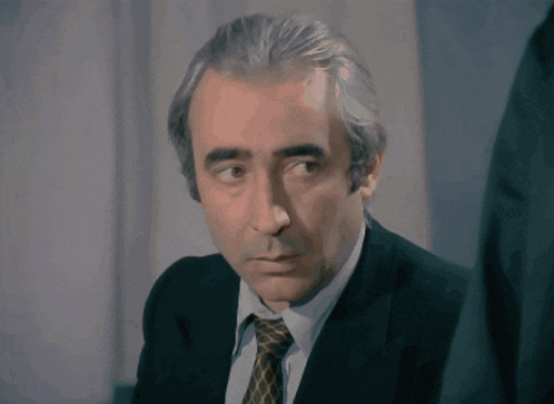 a man in a suit and tie looks to the side