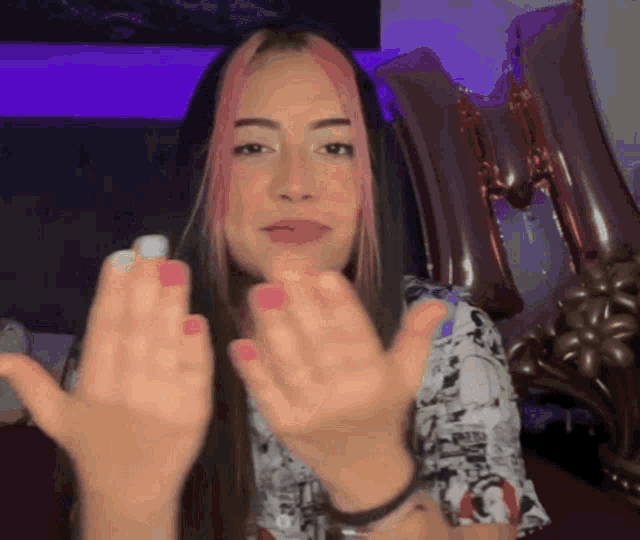 a woman with pink hair and white nails is giving a high five