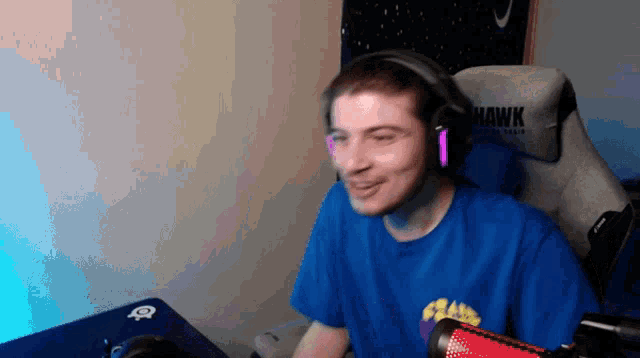 a man wearing headphones is sitting in a chair that says hawk on it