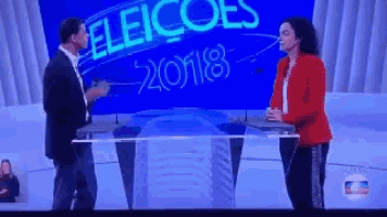 a man and woman are standing in front of a sign that says eleicoes