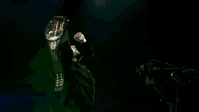 a man in a black hoodie is singing into a microphone in a dark room