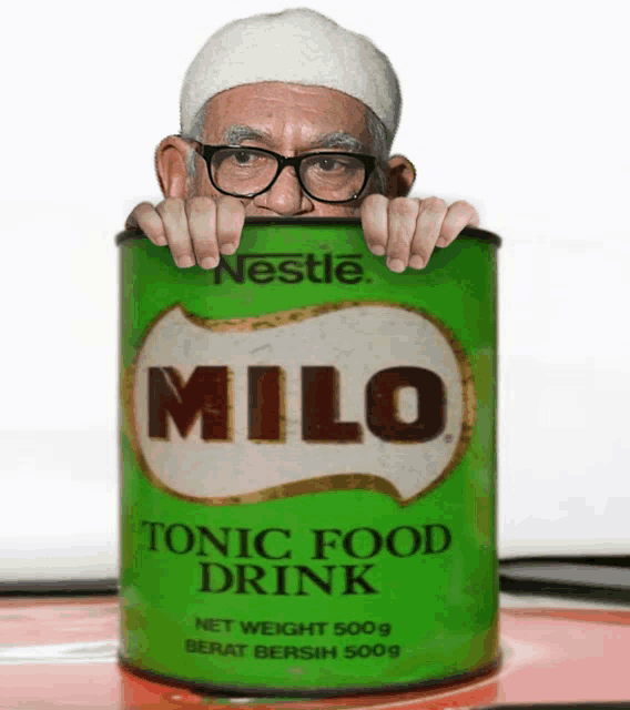 a can of milo tonic food drink is being held by a man wearing glasses