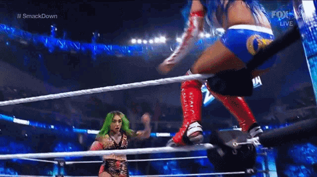 two women are wrestling in a wrestling ring and one of them is wearing green hair .