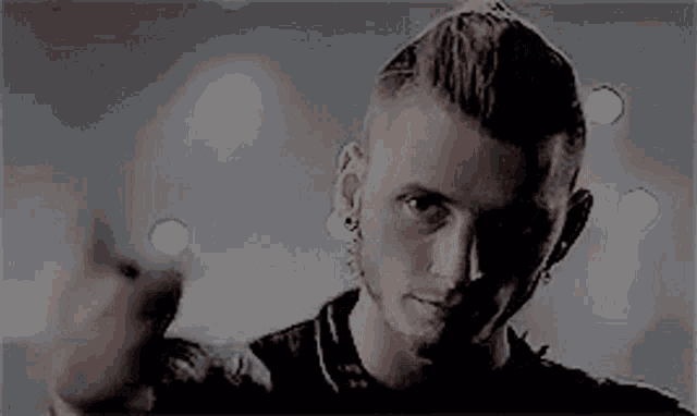 a man with a shaved head is pointing at the camera in a black and white photo .