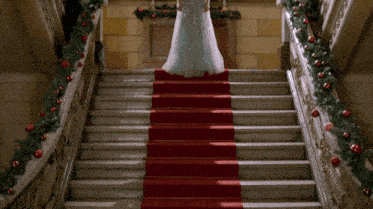 a woman in a wedding dress stands on a set of stairs