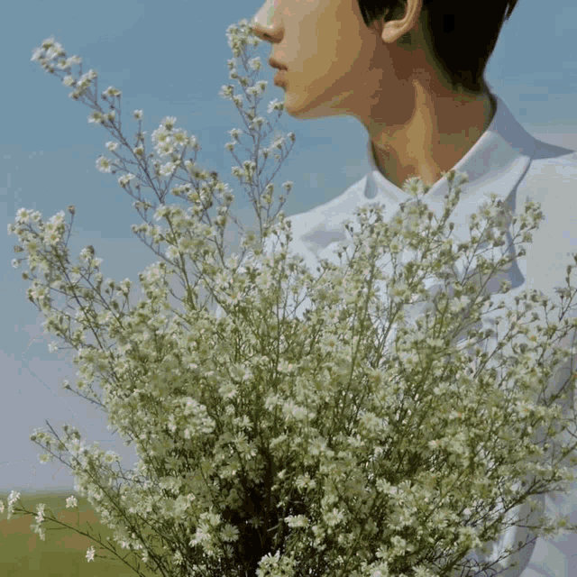 a man in a white shirt is holding a large bouquet of white flowers