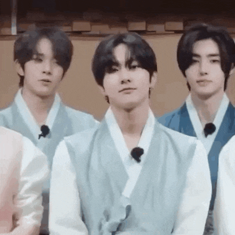 a group of young men wearing traditional clothes are standing next to each other in a room .