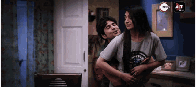a man and a woman are hugging in a room with the word alt on the bottom