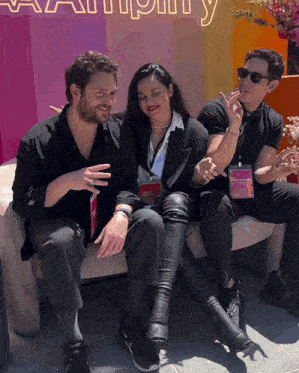 three people sit on a couch in front of a sign that says ' amplify '