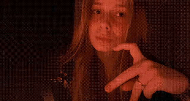 a woman is making a heart shape with her fingers
