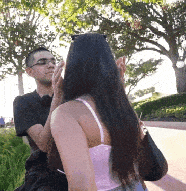 a man is touching a woman 's face in front of trees