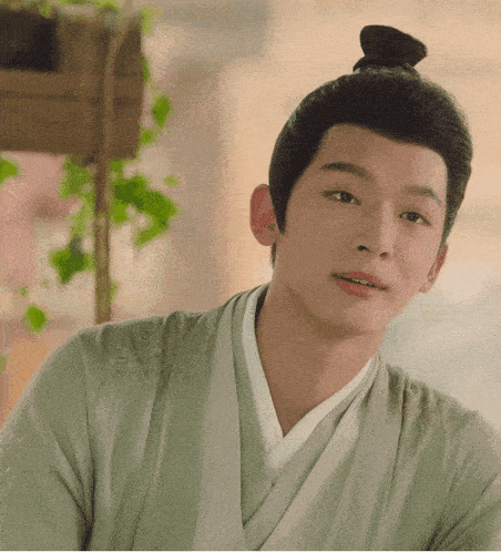 a young man with a bun on his head looks at the camera