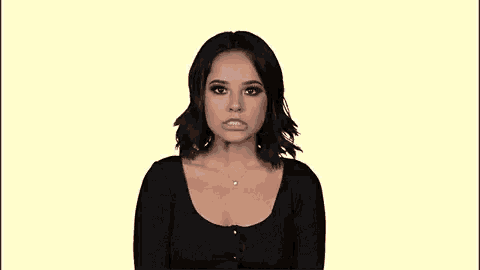 a woman in a black top and necklace is making a face .