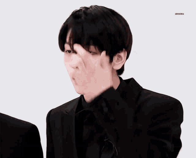 a man in a black suit and tie is making a face