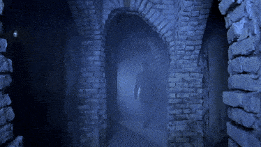 a man in a white suit walks down a dark hallway