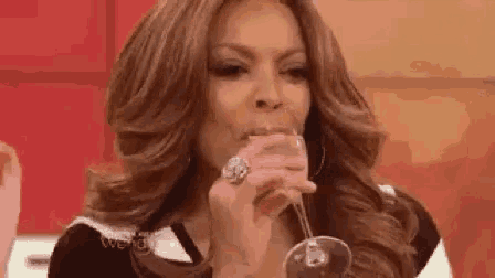 a woman is drinking a glass of wine while wearing a ring .