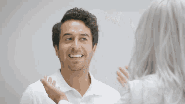a man in a white shirt is smiling and looking at a woman in a white shirt
