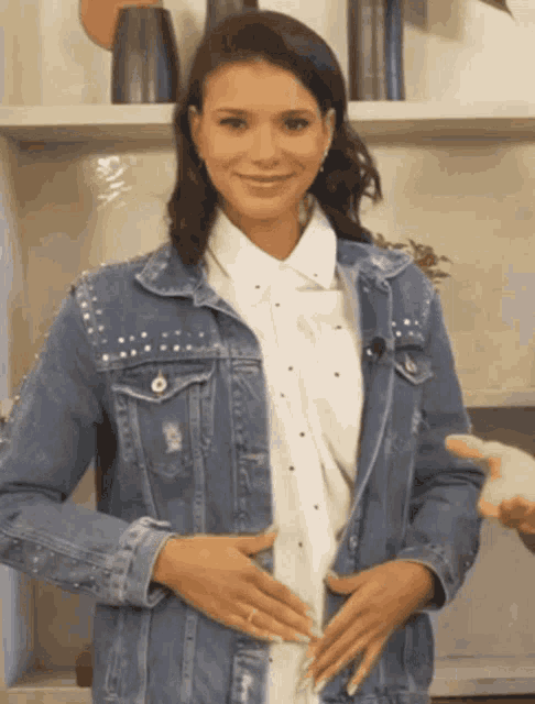 a woman wearing a denim jacket and a white shirt is smiling