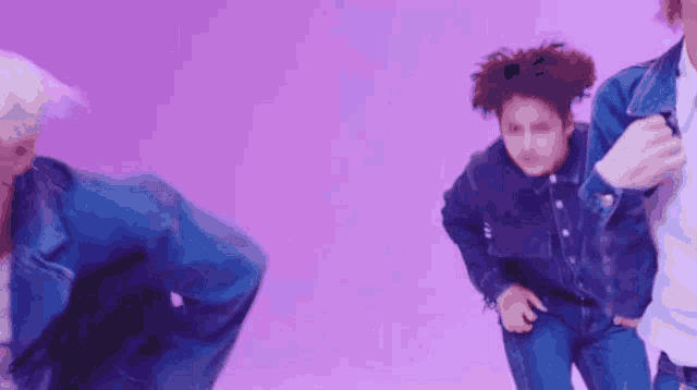 a group of young men are dancing on a stage in front of a purple background .
