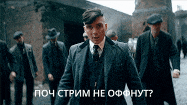 a man in a suit and tie stands in front of a group of men with russian writing on them