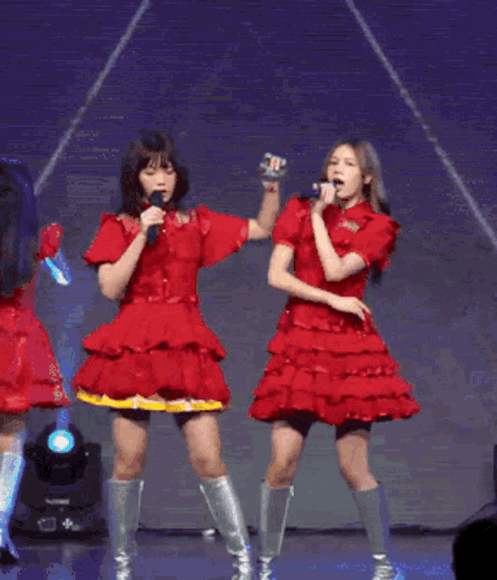 two women in red dresses singing into microphones