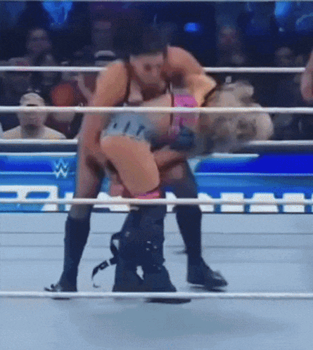 a man and a woman are wrestling in a wrestling ring with a crowd watching