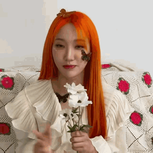 a woman with orange hair has a butterfly on her face and is holding flowers
