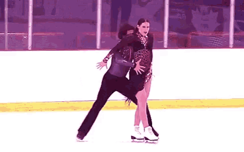 a man and a woman are ice skating on a rink together .
