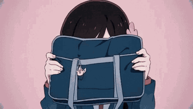 a girl is covering her face with a blue purse .