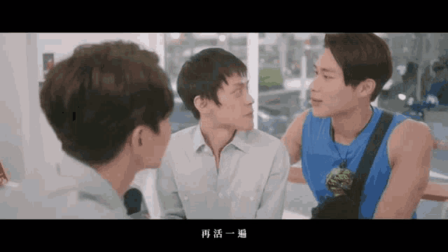 a man in a blue tank top talks to another man