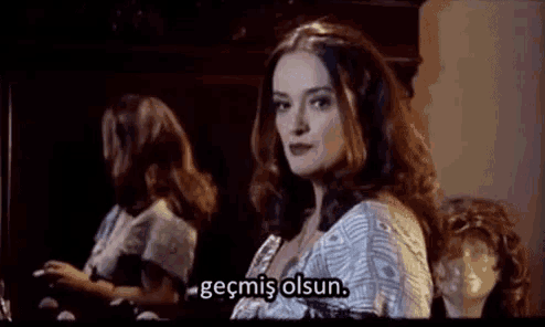 a woman is standing in front of a mirror with a caption that says ' geçmiş olsun ' on it .