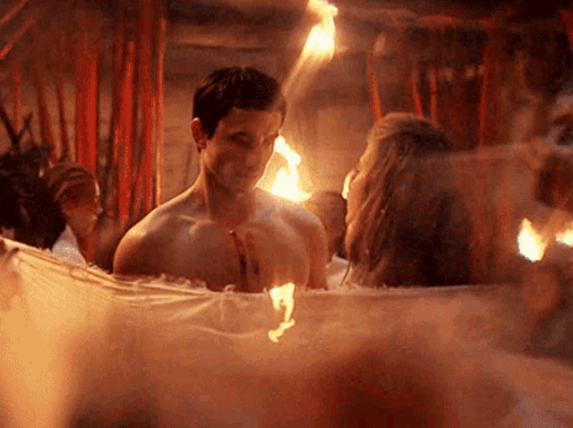 a man and a woman are taking a bath in a bathtub surrounded by flames .
