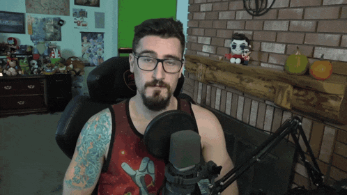 a man wearing glasses and a tank top is talking into a microphone