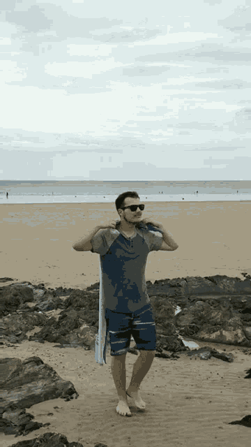 a man standing on a beach with a towel on his shoulders