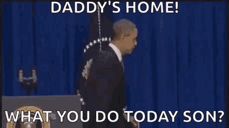 daddy 's home ! what you do today son ? a man in a suit is walking out of a room .