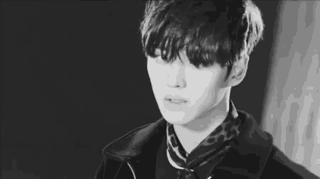 a black and white photo of a young man wearing a leopard print scarf and a jacket .