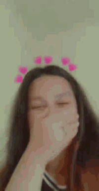 a close up of a woman covering her face with her hand with hearts around her head .