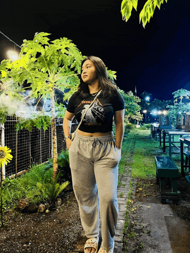 a woman wearing a metallica shirt stands in a garden