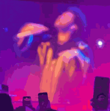 a man in a gold jacket is standing in front of a purple background