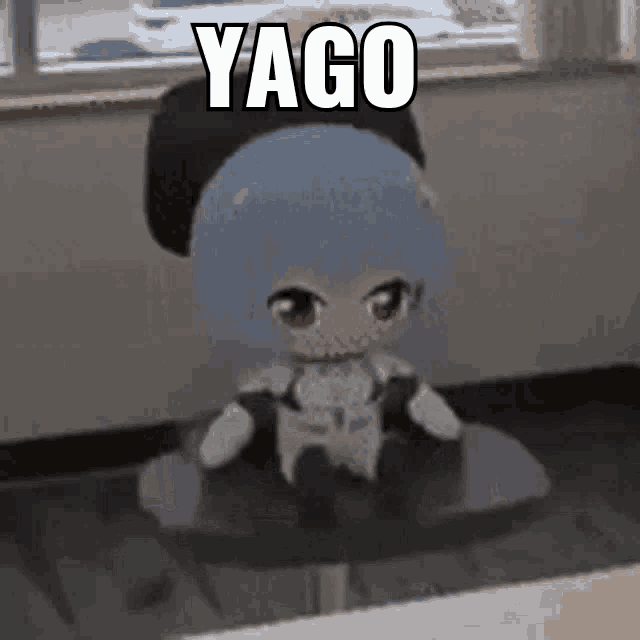 a stuffed doll is sitting on a table with a caption that says yago .