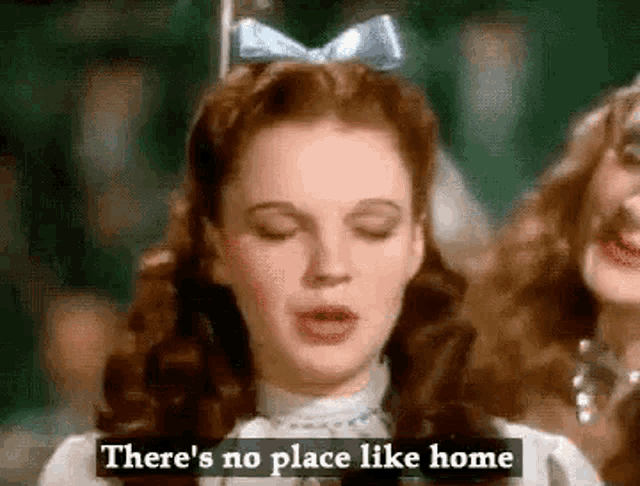 a woman in a white dress with a blue bow in her hair is singing a song from the wizard of oz .