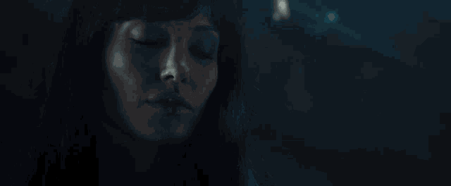 a close up of a woman with her eyes closed in a dark room .