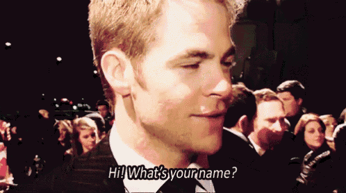a man in a suit and tie asks " what 's your name " in front of a crowd