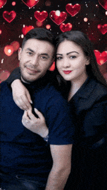 a man and a woman are posing for a picture with red hearts in the background