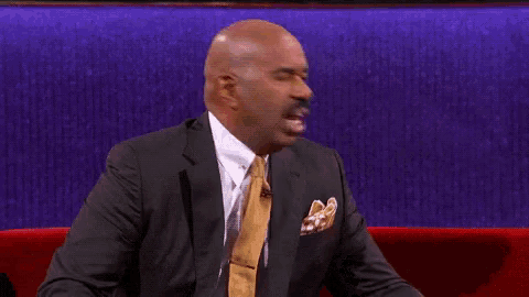 a man in a suit and tie is sitting on a red couch with his mouth open