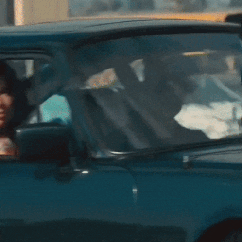 a woman in a plaid shirt driving a blue car
